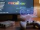 Controller da gioco su scrivania con grafica olografica che mostra la mappatura dei tasti Recalbox e schermo con interfaccia emulatore sullo sfondo.